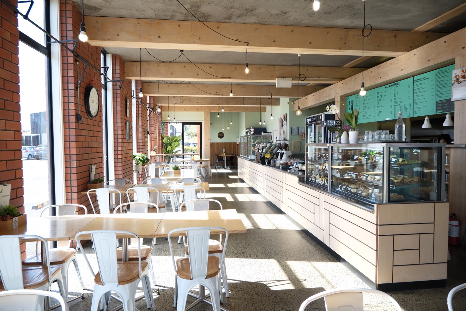 Inside Coffee Nation, with sunlit seating, wooden tables and the food cabinet